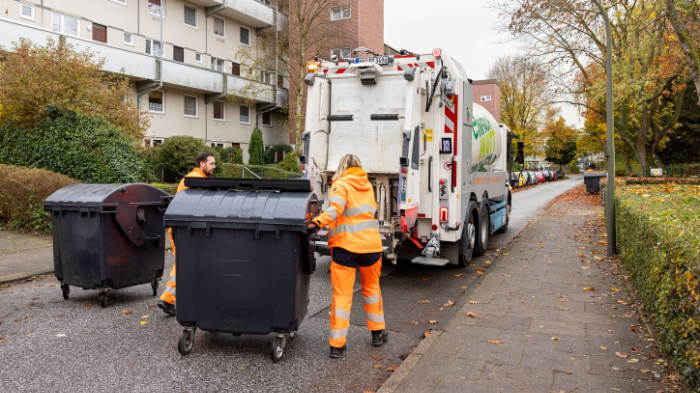 Kolleg:innen in Orange bei der Abfuhr der Restmülltonne