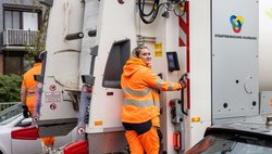 Eine Kollegin in Orange bei der Müllabfuhr