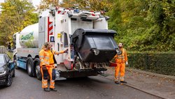 Zwei Kolleg:innen an der Schüttung eines Müllfahrzeugs