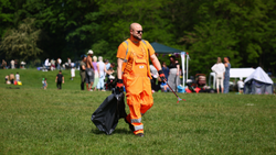 Kollege in Orange befreit eine Grünanlage von Müll