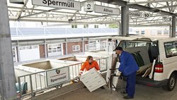 Eine Recyclinghof-Mitarbeiterin hilft einem Kunden