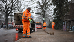 SRH-Mitarbeiter streut ein Kies-Sand-Gemisch