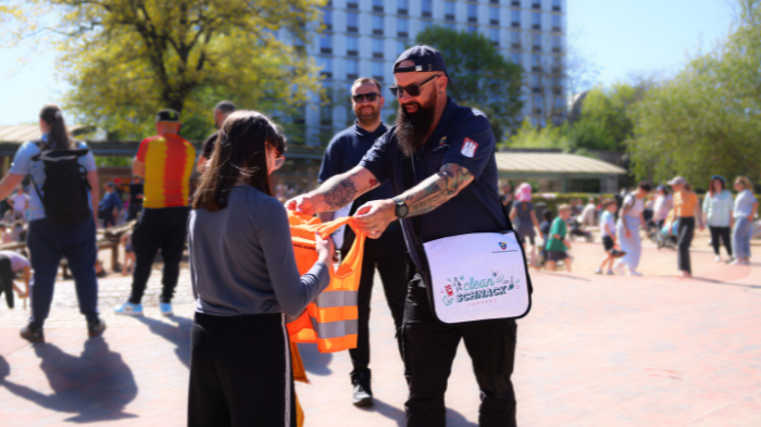 Waste Watcher gibt einem Kind eine Warnweste Waste Watcher gibt einem Kind eine Warnweste