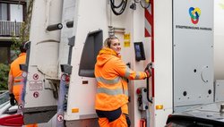 SRH-Mitarbeitende auf dem Trittbrett eines Müllwagens