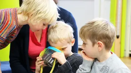 Drei Kinder, die etwas in einem Gefäß beobachten